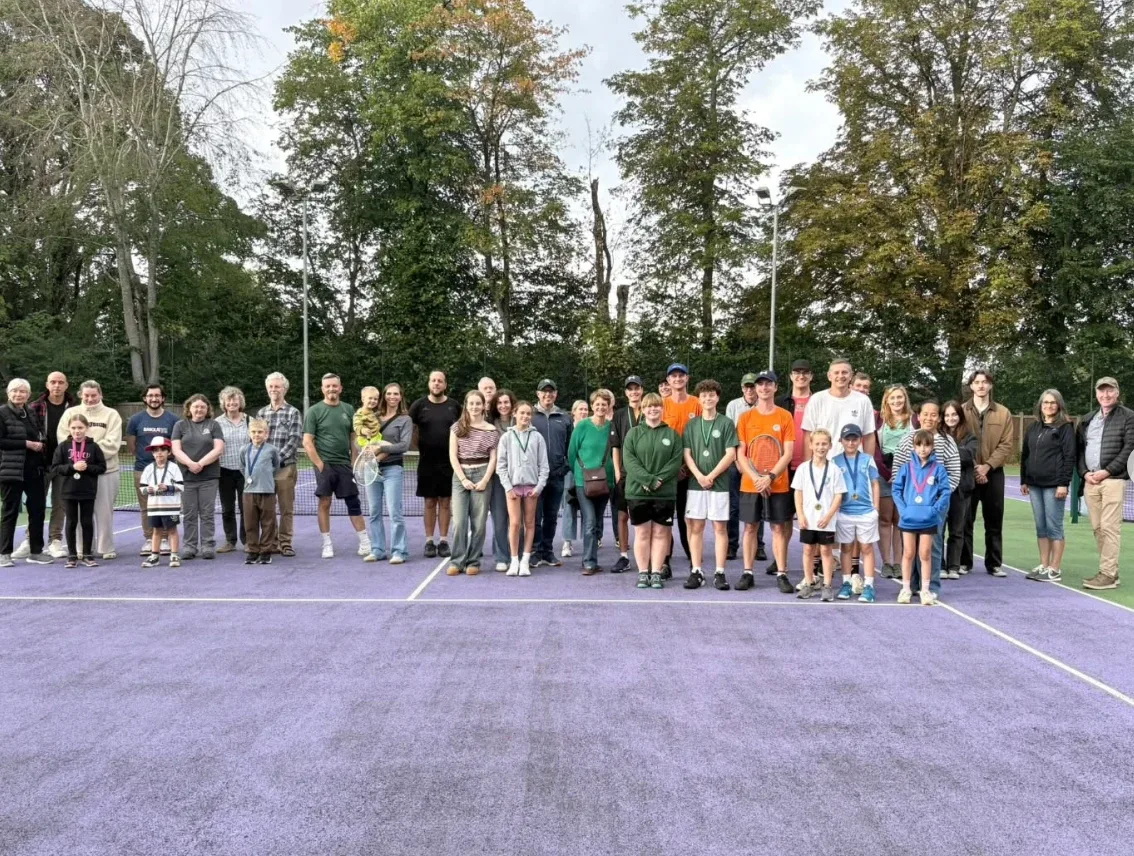 Players, families and coaches lined up together on a purple court at an MH Tennis event