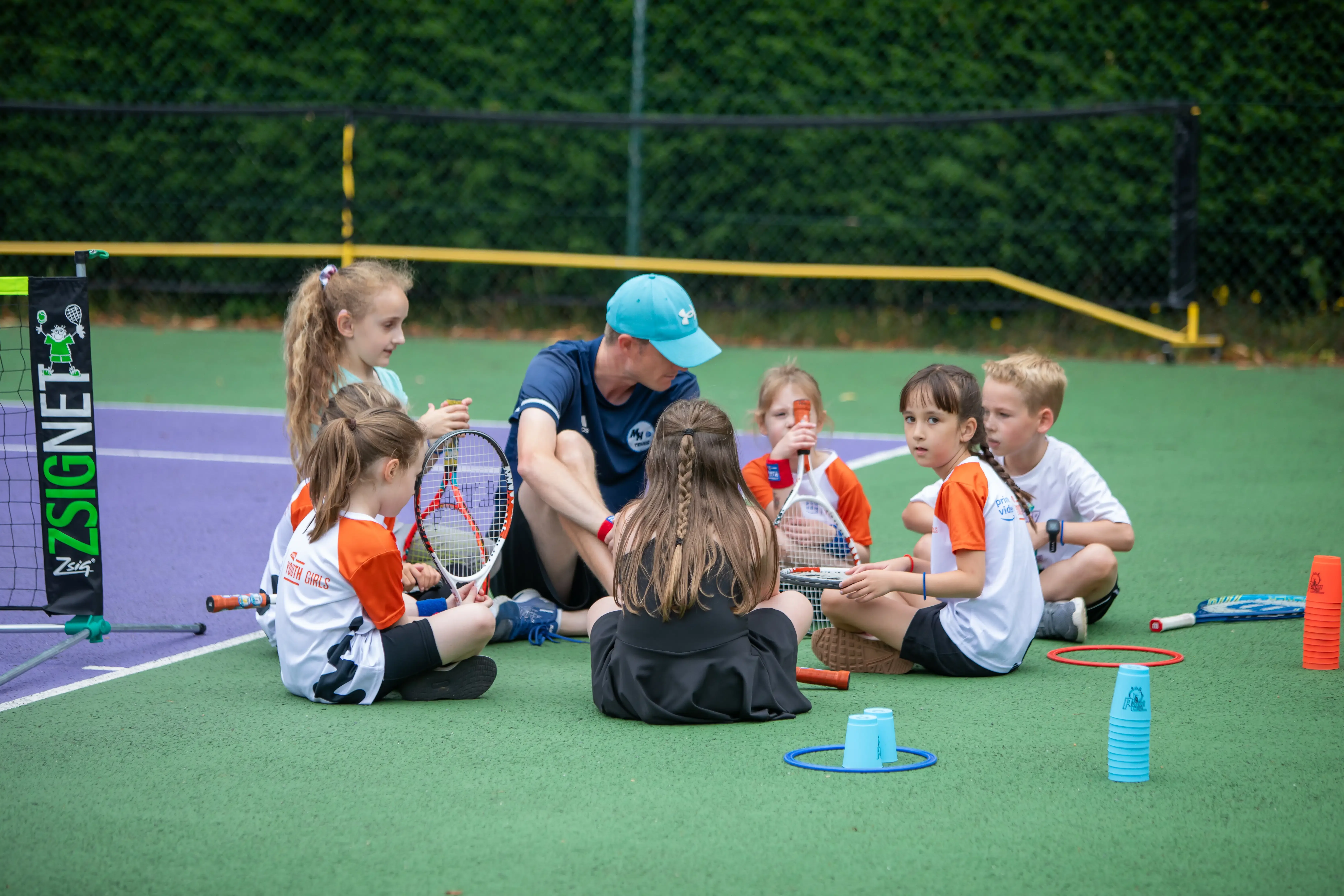 Children listening and learning together during a supportive MH Tennis coaching session