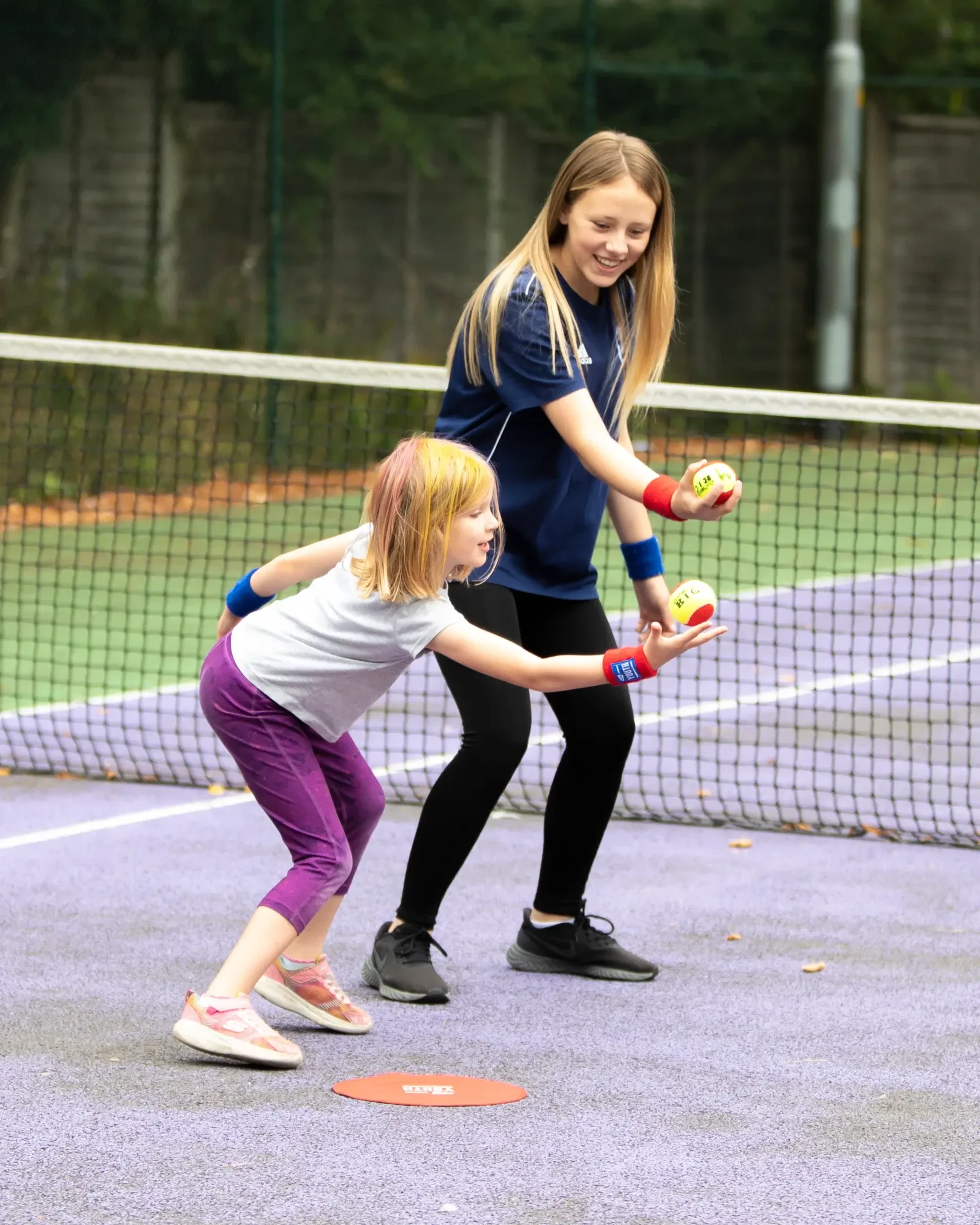 A Young Leader tossing a soft ball for a young girl to catch on court