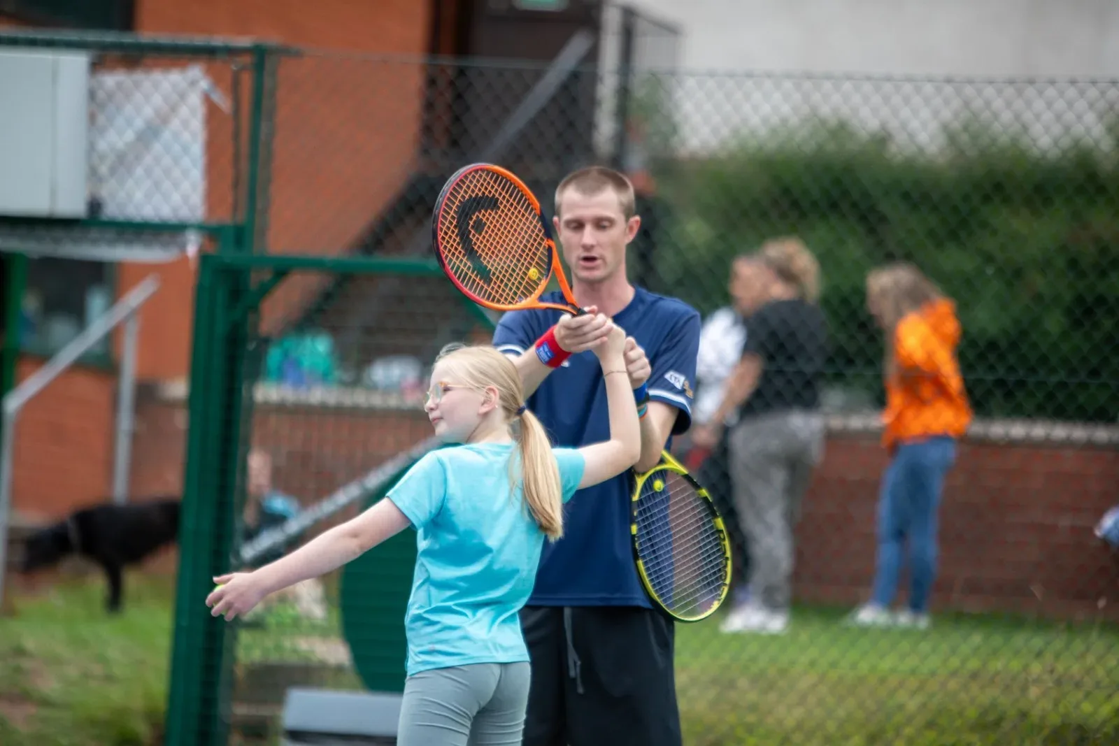 A coach helping a young player with her forehand
